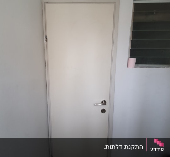 דלת לבנה עם ידית מתכת ליד חלון קטן